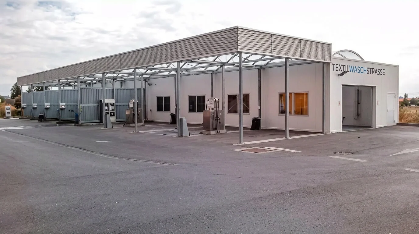 Eine moderne Selbstbedienungs-Autowaschanlage mit mehreren Waschplätzen an einem bewölkten Tag. Eine moderne Selbstbedienungs-Autowaschanlage mit mehreren Waschplätzen an einem bewölkten Tag.