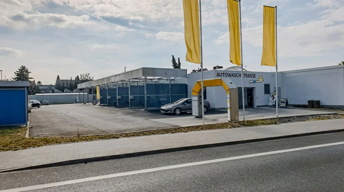 Eine Autowaschanlage mit gelben Fahnen und einem silbernen Auto, das unter einem Vordach geparkt ist. Eine Autowaschanlage mit gelben Fahnen und einem silbernen Auto, das unter einem Vordach geparkt ist.