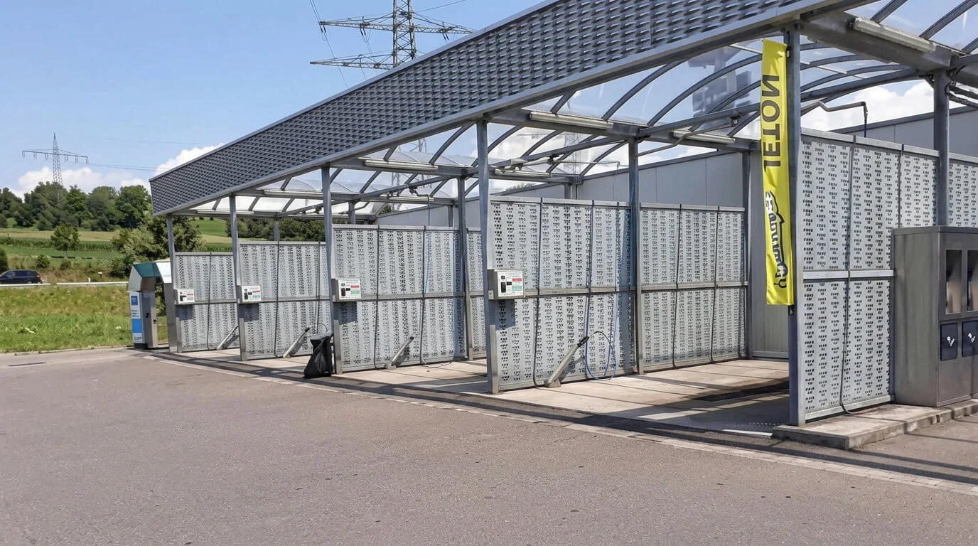 Selbstbedienungs-Autowaschplätze im Freien mit Ausrüstung und einem gelben Schild an einem sonnigen Tag. Selbstbedienungs-Autowaschplätze im Freien mit Ausrüstung und einem gelben Schild an einem sonnigen Tag.