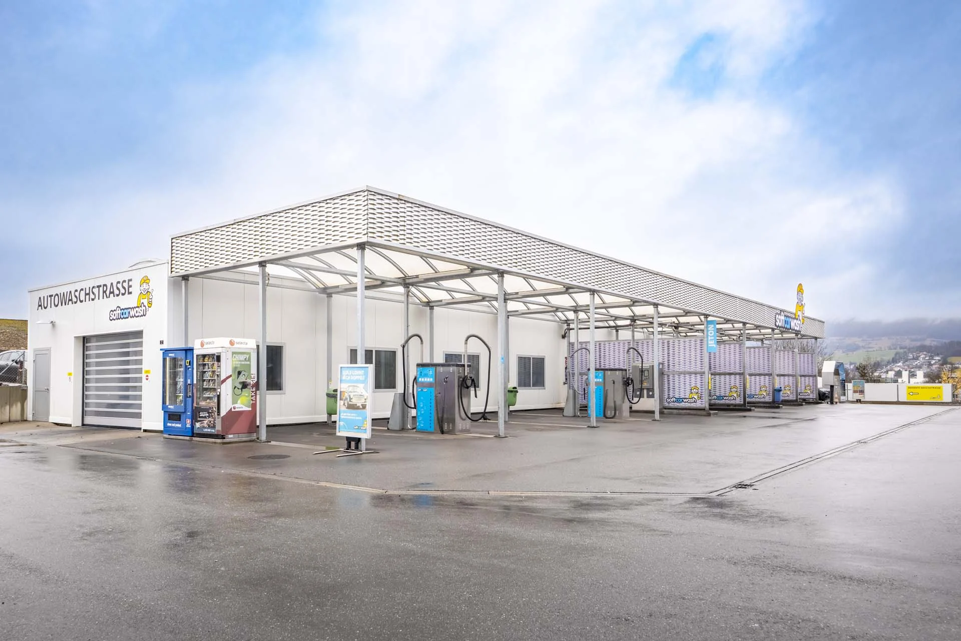 Eine moderne Autowaschanlage mit Waschplätzen und Staubsaugerstationen an einem bewölkten Tag. Eine moderne Autowaschanlage mit Waschplätzen und Staubsaugerstationen an einem bewölkten Tag.