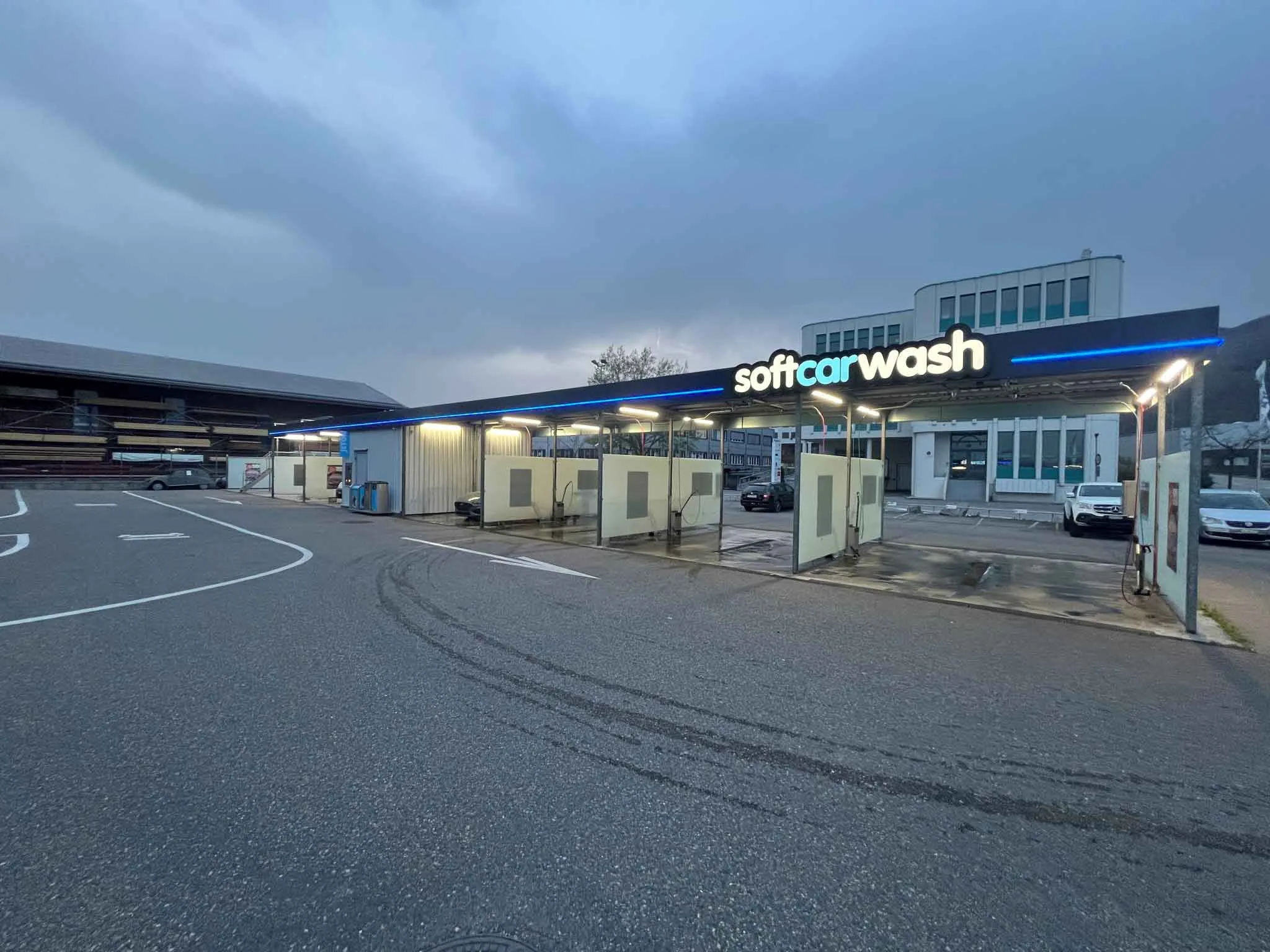 Selbstbedienungs-Autowaschanlage im Freien mit Waschplätzen, neben einem Gebäude, unter bewölktem Himmel. Selbstbedienungs-Autowaschanlage im Freien mit Waschplätzen, neben einem Gebäude, unter bewölktem Himmel.
