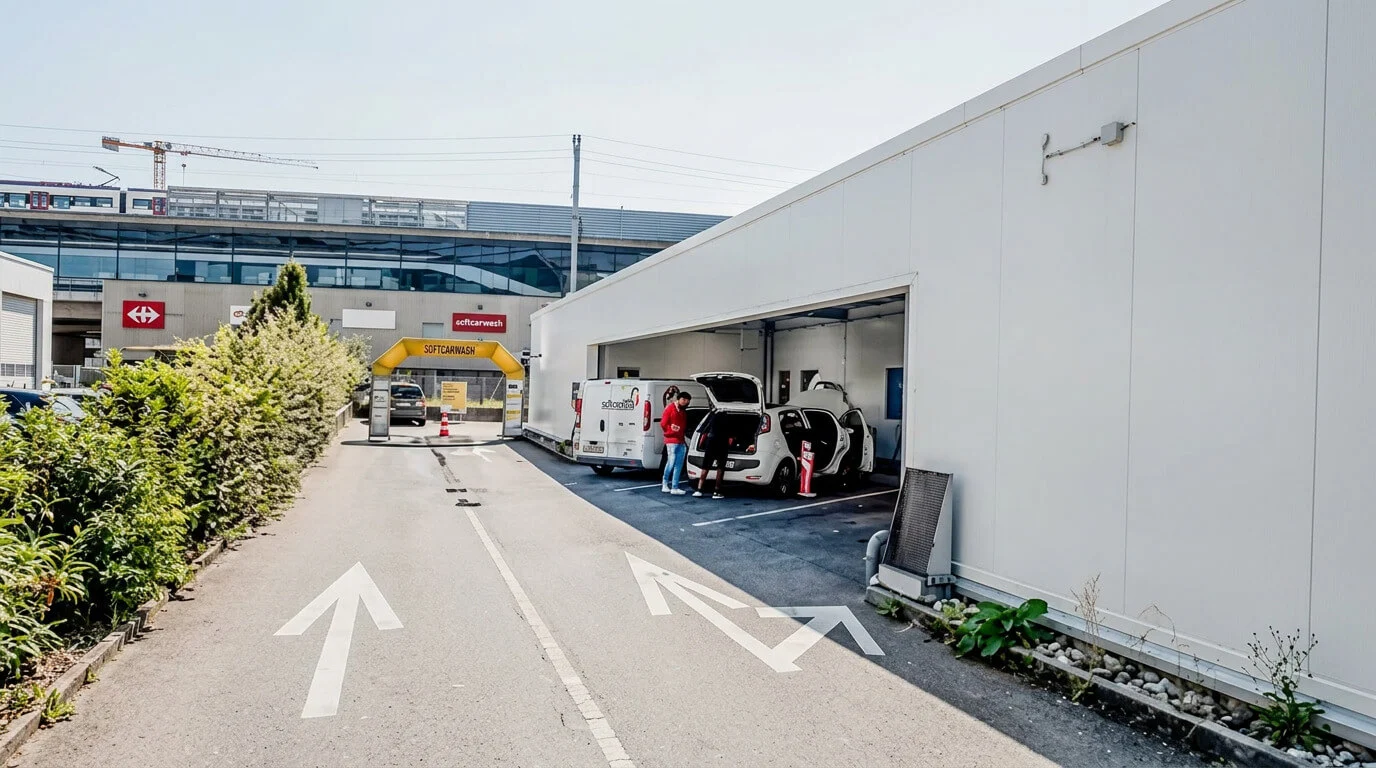 Zwei Personen laden vor einem weißen Gebäude in der Nähe einer Einfahrt mit aufgemalten Pfeilen Gegenstände in Autos. Zwei Personen laden vor einem weißen Gebäude in der Nähe einer Einfahrt mit aufgemalten Pfeilen Gegenstände in Autos.