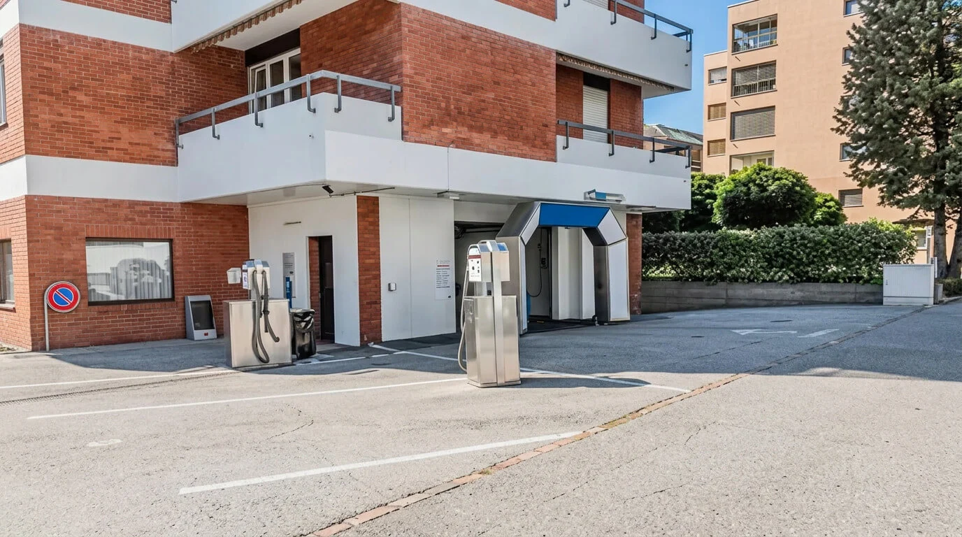 Zwei Selbstbedienungstankstellen auf einem leeren Parkplatz neben einem Backsteingebäude. Zwei Selbstbedienungstankstellen auf einem leeren Parkplatz neben einem Backsteingebäude.